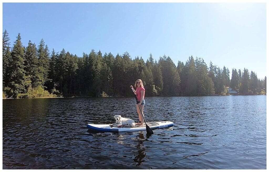 girl paddle boarding with Golden Retriever laying on front